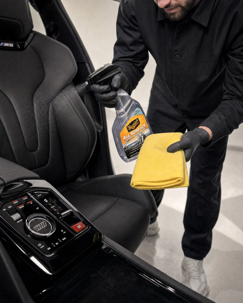 Daniel mit Meguiars ‚ALL SURFACE‘ Interior Cleaner und frischem Mikrofasertuch am Cockpit eines BMW M5 — gezeigt im Artikel „