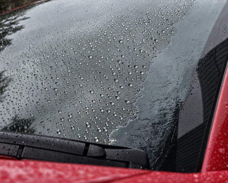 Regenabweiser im Test: Tropfen perlen auf versiegeltem Glas, am unversiegelten Rand liegt ein Wasserfilm